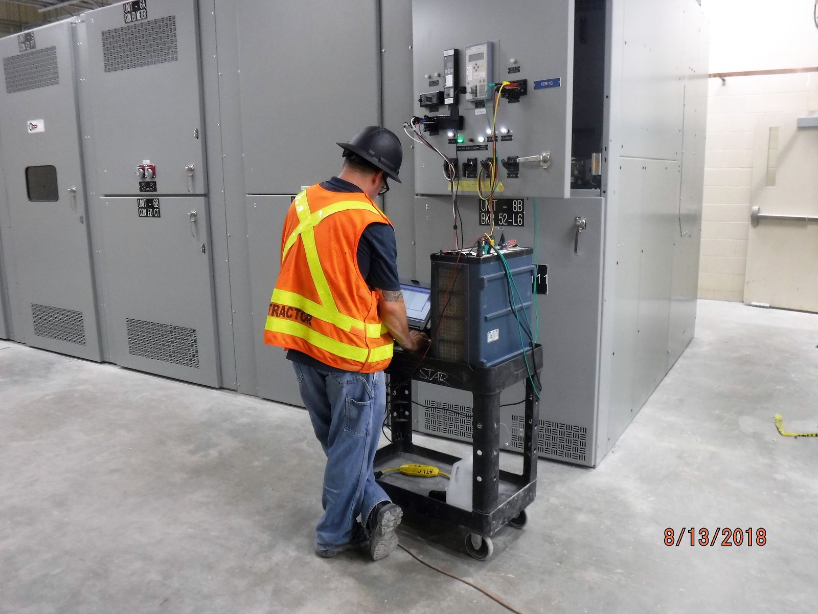 Technicians testing switchgear inside a power substation switchgear room